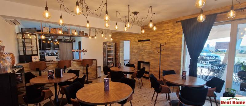 Gasztró terek függő lámpákkal, fa dekorációval és hangulatos ülőhelyekkel.