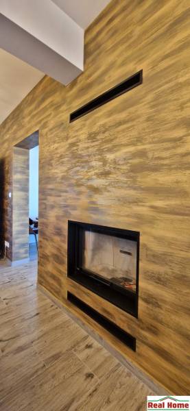 Beltéri vendéglátó helyiség kandallóval és fa dekorációjú padlóval.