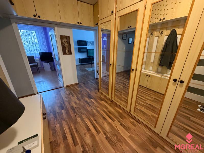 Előszoba egy háromszobás lakásban fa dekor padlóval és tükrös szekrényekkel.