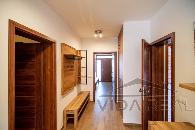 Folyosó a családi házban fa dekorációval a padlón és a bútorokon.