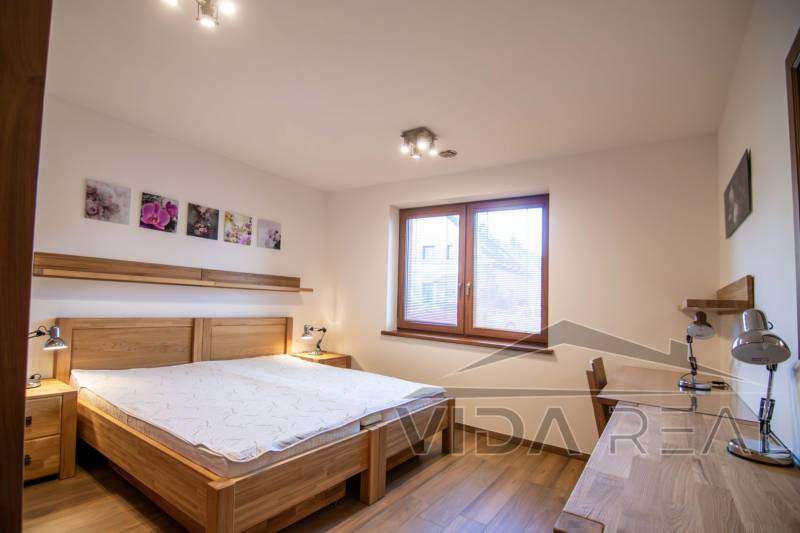 Hálószoba családi házban ággyal, éjjeli lámpákkal és fa dekor padlóval.