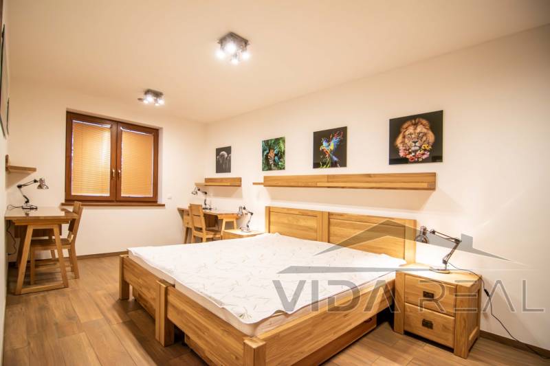 Hálószoba családi házban, fa mintázatú padlóval, képekkel és íróasztalokkal.