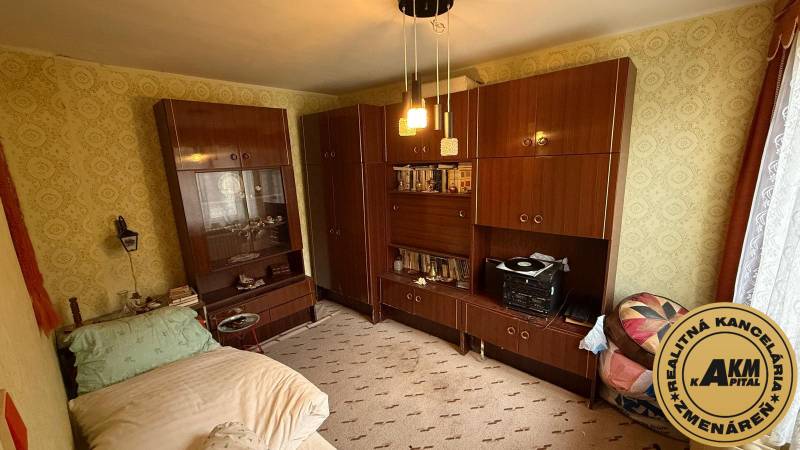 Szoba egy családi házban bútorokkal, ággyal és mintás tapétával a falakon.