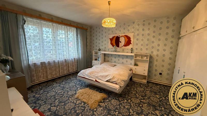 Hálószoba családi házban virágos szőnyeggel és nagy ablakkal.