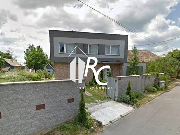 Családi ház Bystričkán gondozott kerttel és magas kerítéssel az utca mentén.