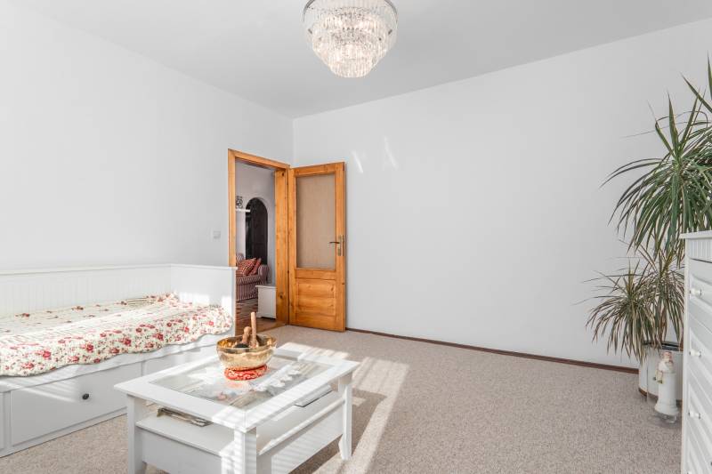 Világos szoba virágmintás ágyneművel, asztallal és csillárral egy 4 szobás lakásban.