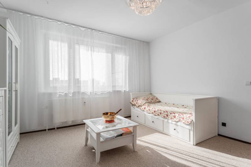 Világos szoba egy 4 szobás lakásban kanapéval, asztallal és függönyökkel az ablakon.