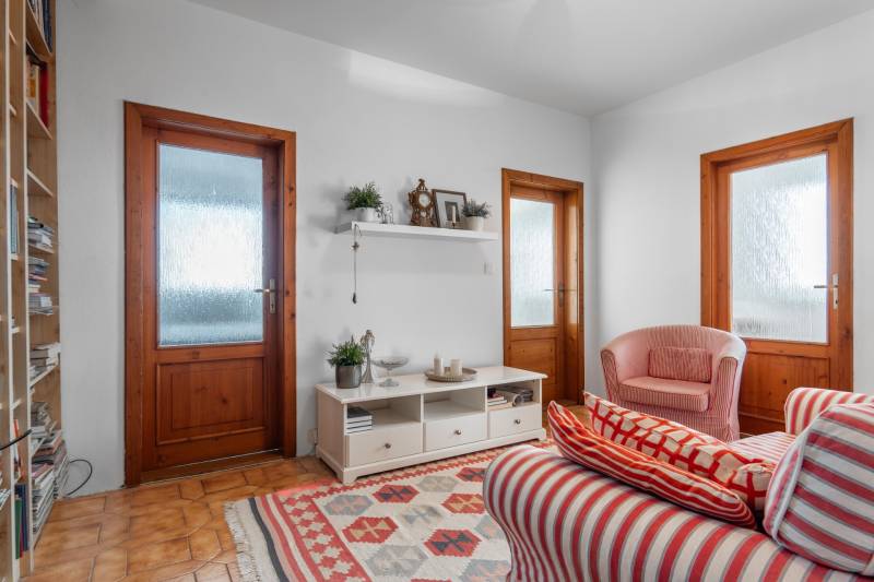 Nappali egy négy szobás lakásban piros csíkos fotelekkel és falra szerelt polccal.