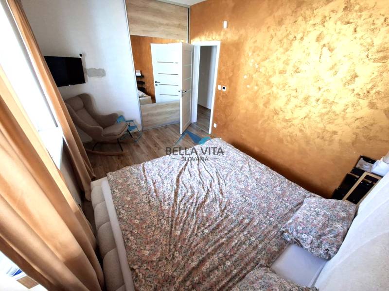 Hálószoba családi házban, fa dekoros padlóval, barna függönyökkel és mintás ággyal.