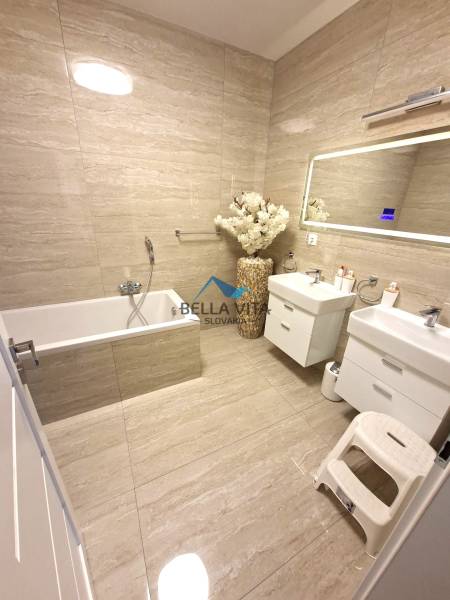 Fürdőszoba családi házban káddal, dupla mosdóval és dekoratív vázával.