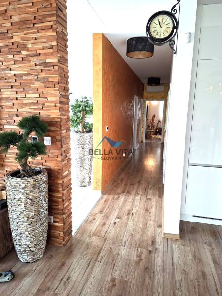 Családi ház belső tere dekoratív fallal, fa mintázatú padlóval és modern kiegészítőkkel.