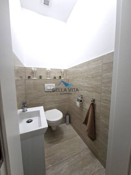 Kompakt WC egy családi házban, fa dekor padlóval, dekoratív részletekkel.