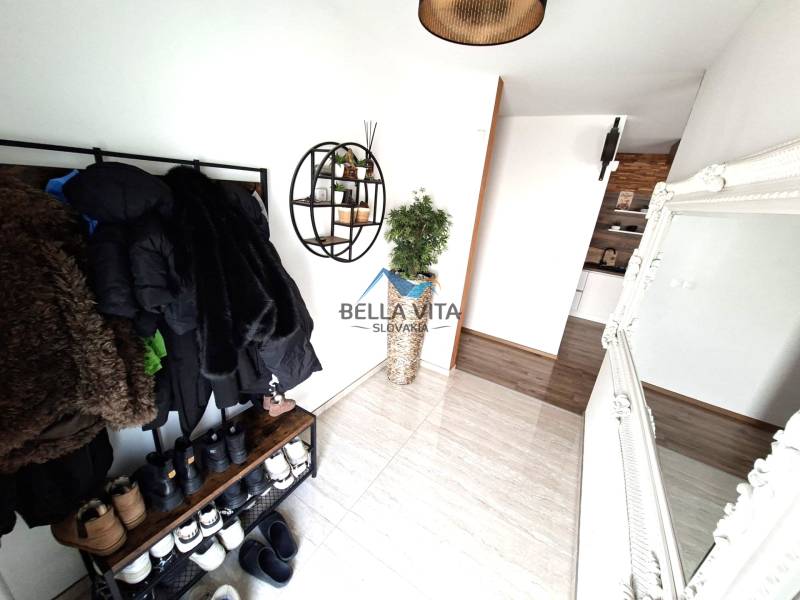 Családi ház belső tere ruhafogassal, tükörrel és fa dekorációjú padlóval.