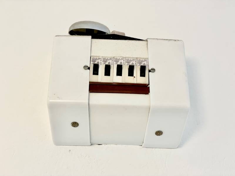 Egy szobás lakás fehér műanyag burkolattal és kapcsolókkal.