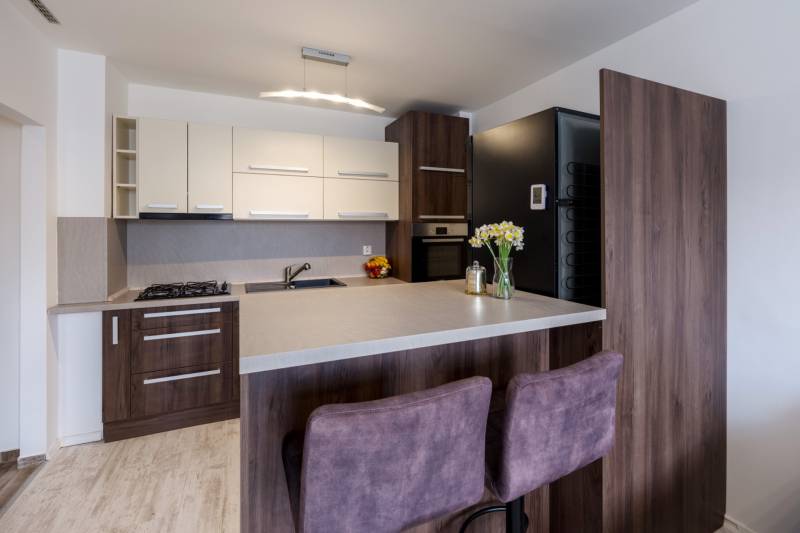 Konyha egy kétszobás lakásban bárpulttal, pult és padló fa dekorációval, székek.