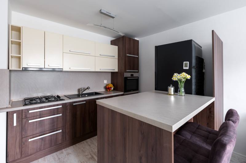 Konyha egy kétszobás lakásban fa dekor padlóval, bárpulttal és modern felszereléssel.