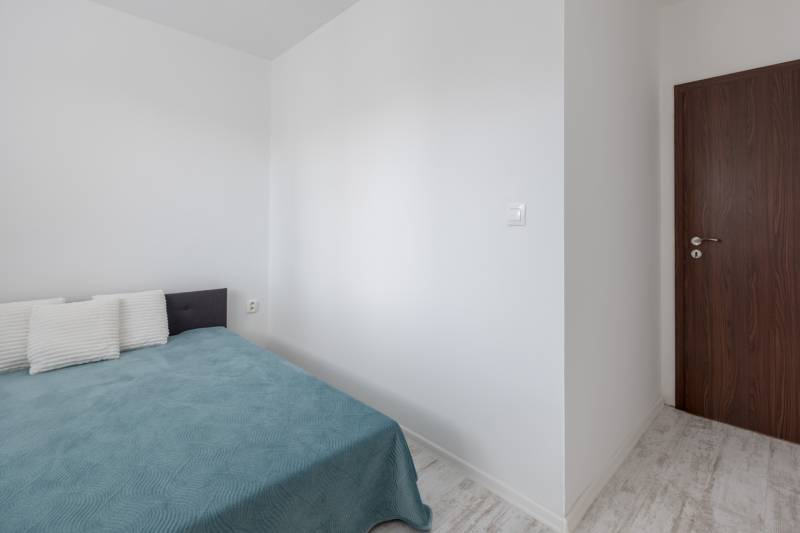 Hálószoba egy kétszobás lakásban ággyal, párnákkal és faajtókkal.