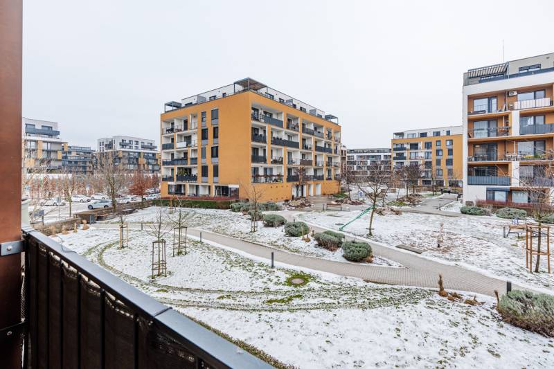 Hóval borított járdákkal és zöldterülettel körülvett épület a Pozsony-Petržalka Béžová utcában.