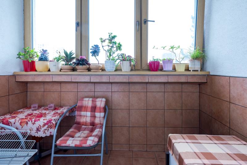 Berendezett 4 szobás lakás virágokkal a párkányon és asztallal, szőnyeggel az erkélyen.