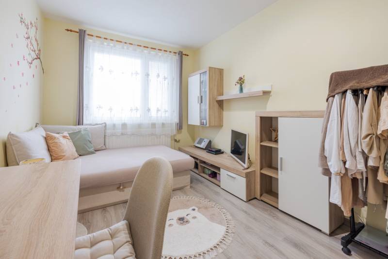 Világos szoba ággyal, íróasztallal és szekrénnyel egy 4 szobás lakásban.