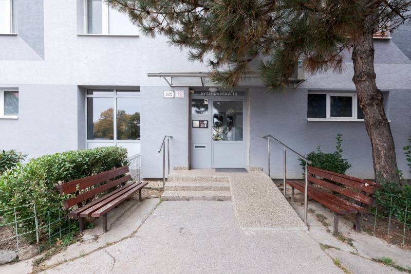 A pozsonyi Vyšehrad utca épületének bejárata - Pozsonyligetfaluban, padokkal és zöldterülettel.