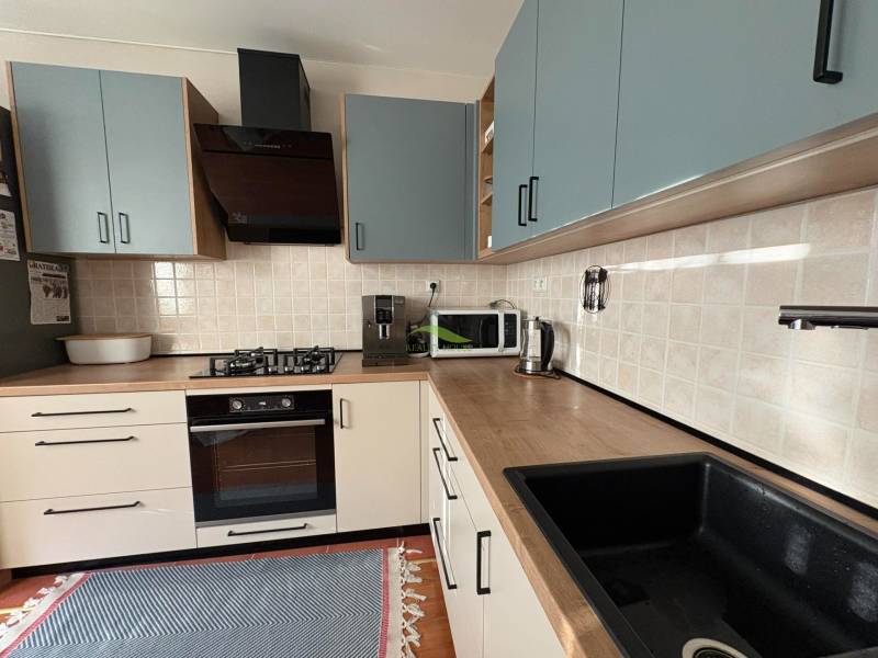 Konyhaszekrény a háromszobás lakásban fa dekor padlóval és háztartási gépekkel.