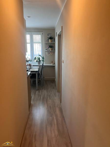 Keskeny folyosó vezet a háromszobás lakásban a világos étkezőbe, ahol növények és dekorációk vannak.