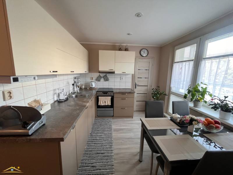 Konyha egy háromszobás lakásban asztallal, készülékekkel és növényekkel.