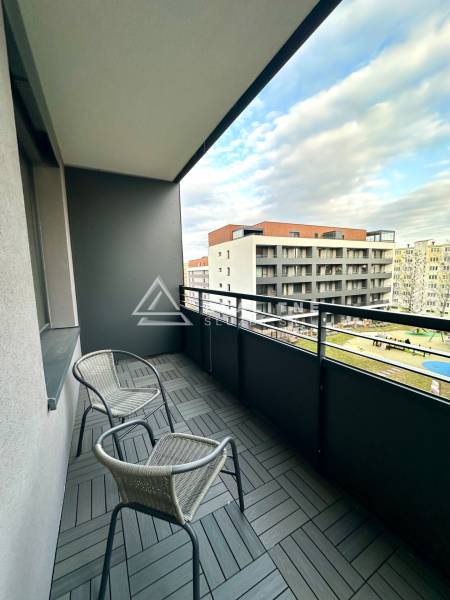 Erkély két székkel és fa dekoros csempékkel, kilátás az épületekre.