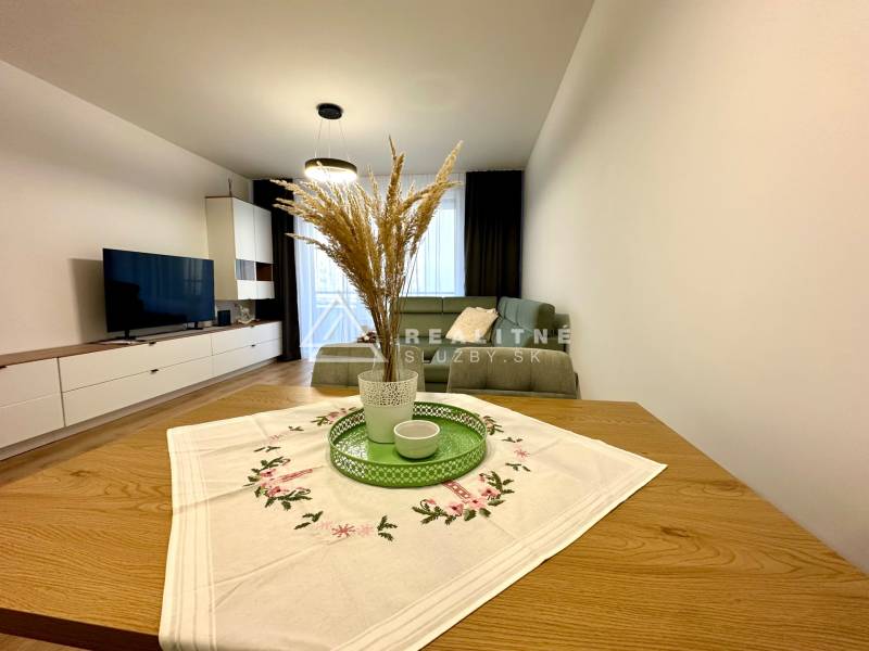 Nappali egy kétszobás lakásban; kanapé, televízió, asztal dekorációval, fa dekoros padló.