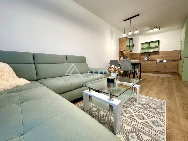 Nappali egy kétszobás lakásban, fa mintázatú padlóval és kényelmes kanapéval.