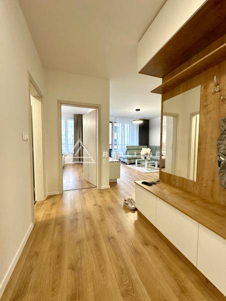 Folyosó egy 2 szobás lakásban fa dekor padlóval és beépített bútorokkal.