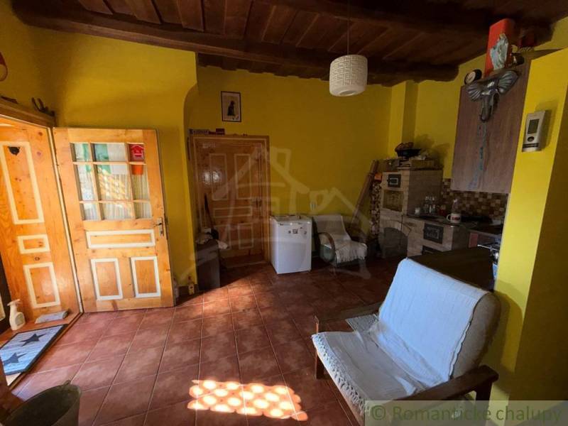 Szoba egy családi házban téglapadlóval, fa mennyezettel és sárga falakkal.