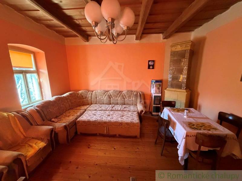 Nappali sarokkanapéval, fa hatású padlóval és cserépkályhával egy családi házban.