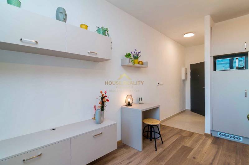 1 szobás lakás belső tere világos bútorokkal és fa dekorációjú padlóval.