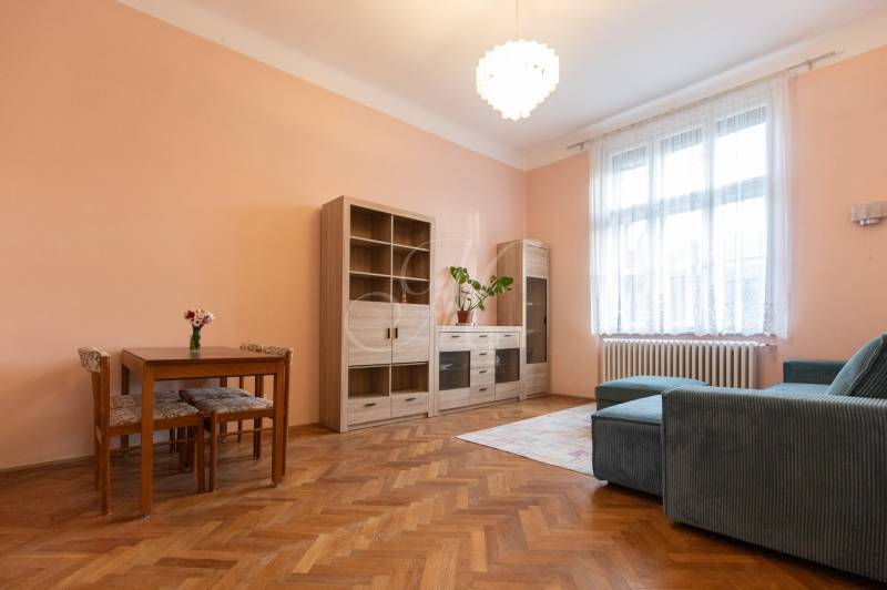 Nappali egy háromszobás lakásban fa dekor padlóval, kanapéval és bútorokkal.