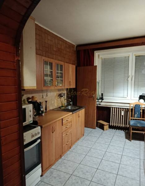 Konyha egy kétszobás lakásban konyhabútorral és csempével, ablak redőnyökkel.