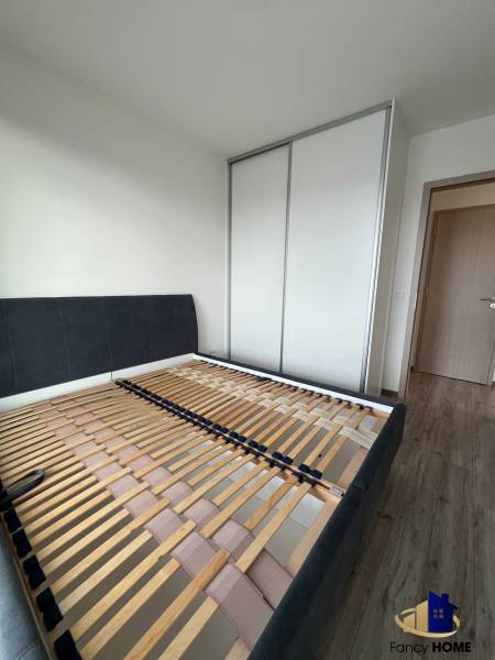 Hálószoba egy háromszobás lakásban ágykerettel és beépített szekrénnyel.