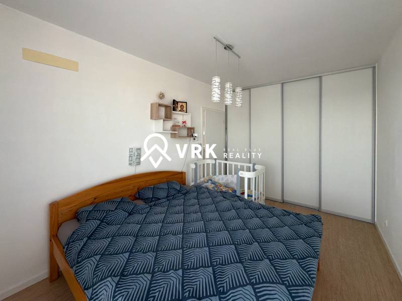 Hálószoba egy háromszobás lakásban franciaággyal, gyerekággyal és fa dekorációjú padlóval.