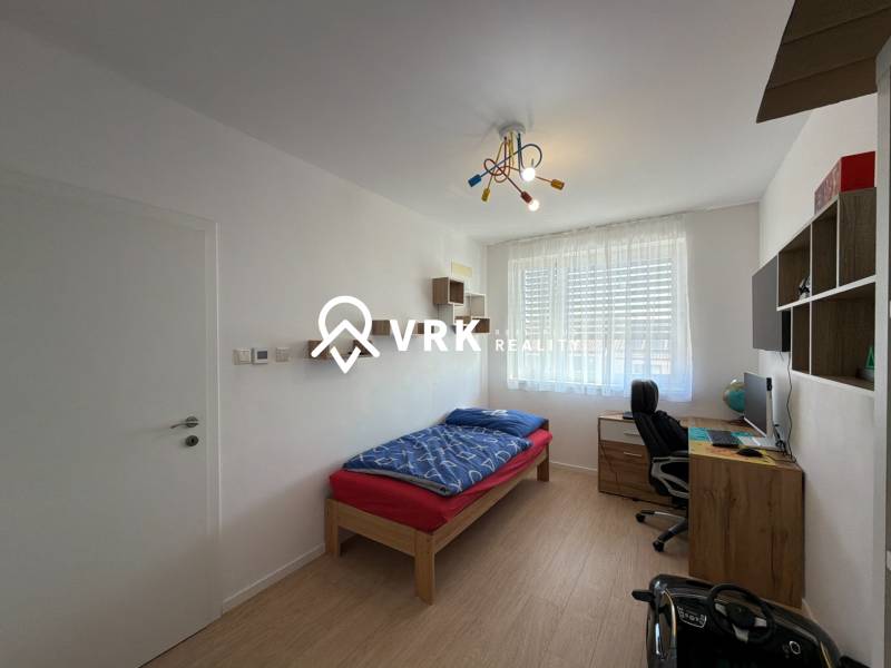 Gyerekszoba egy háromszobás lakásban, fa dekoros padlóval, íróasztallal, ággyal.