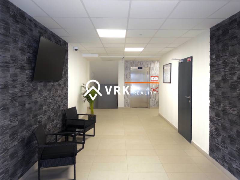 Előszoba egy 3 szobás lakásban, TV-vel a falon és háttérben lifttel.