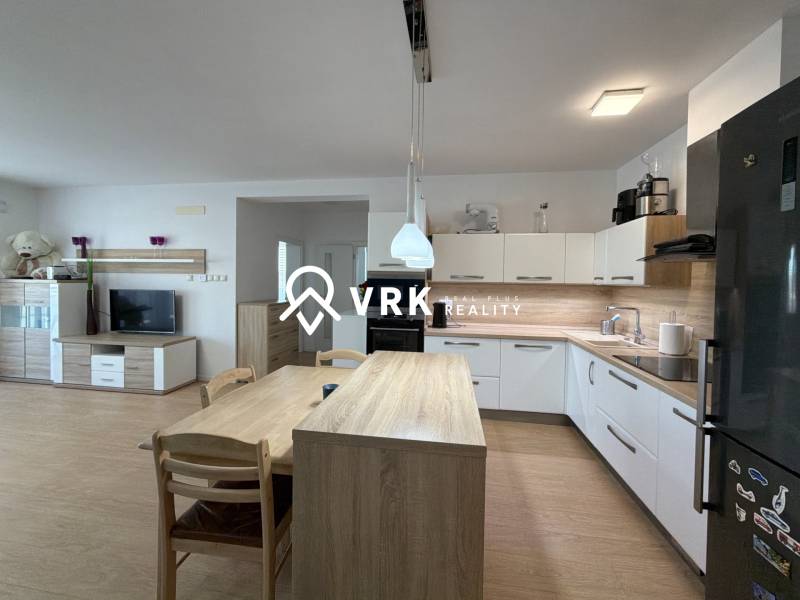 Konyha egy háromszobás lakásban, fa dekoros padló, modern készülékek és étkezőasztal.