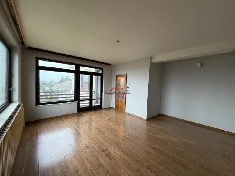 Szoba egy családi házban fa dekoros padlóval és nagy ablakokkal a kertre.