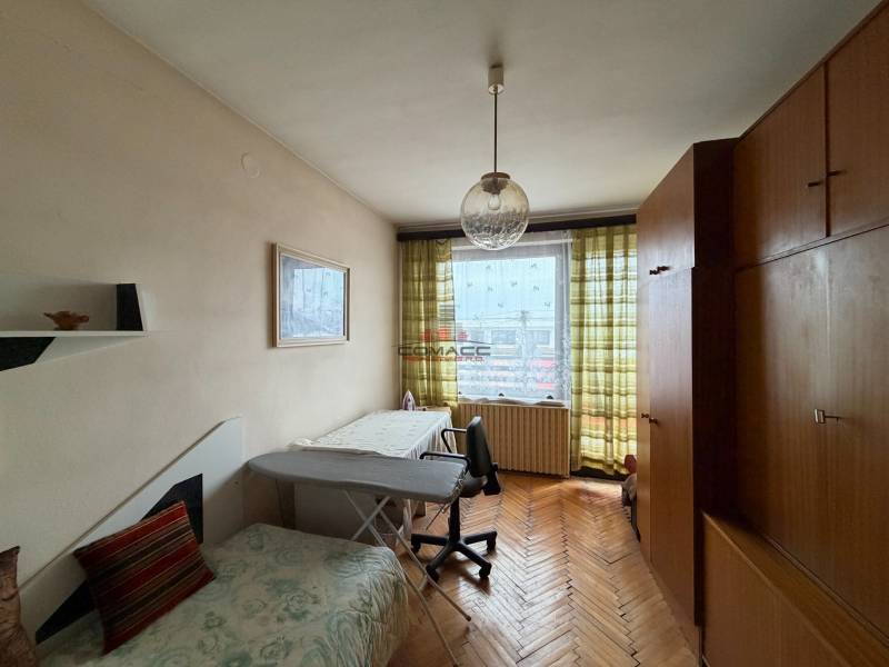 Szoba egy családi házban fa dekor padlóval, kanapéval és nagy szekrénnyel.