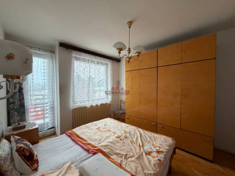 Hálószoba franciaággyal, bútorokkal és fa dekorációjú padlóval egy családi házban.