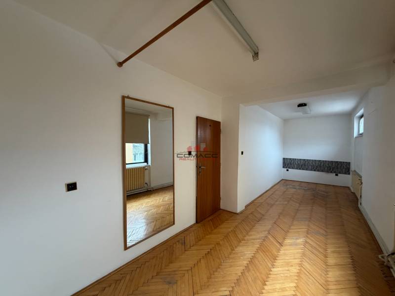 Egy családi ház szobája fa dekorációjú padlóval, tükörrel és ablakkal.