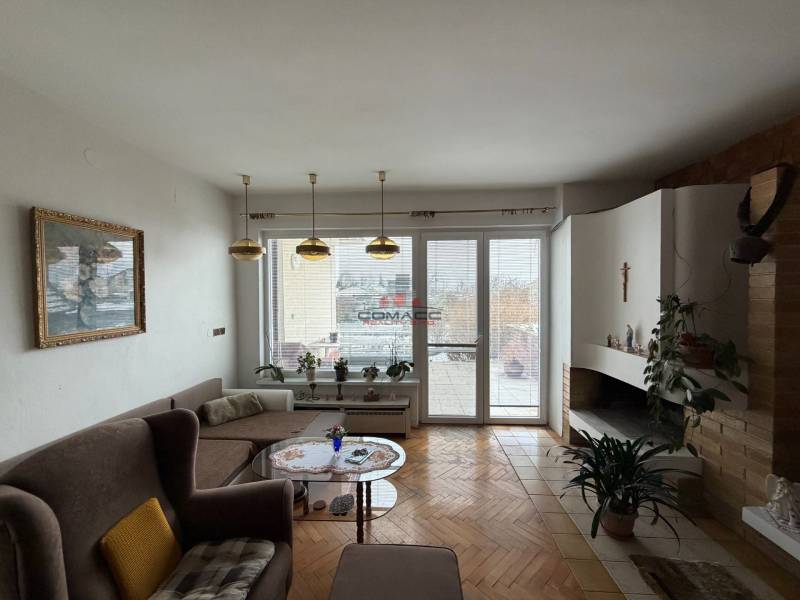 Nappali családi házban kandallóval, kanapéval és fa dekorációjú padlóval.