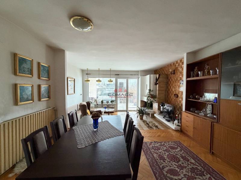 Nappali egy családi házban, fa dekoros padlóval, étkezőasztallal és kandallóval.