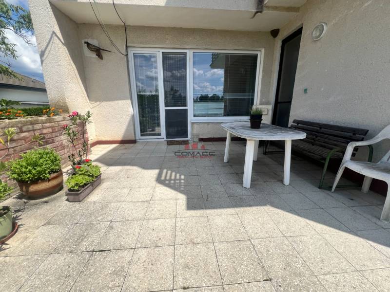 A Tálová utcai családi ház terasza Nagyőrvisen műanyag asztallal és virágokkal.