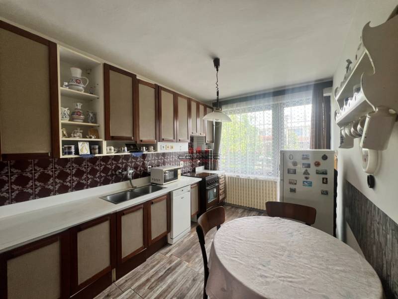 Konyha családi házban fa szekrényekkel, kerek asztallal és fa dekorációjú padlóval.